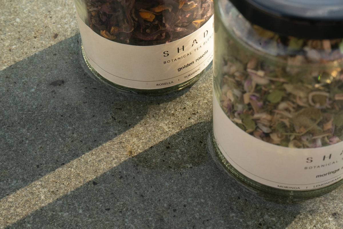 Two jars of Shade Botanicals Tea Blend on a concrete surface.