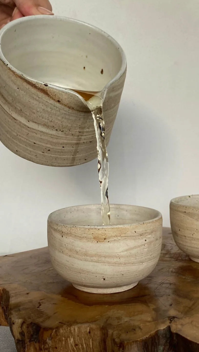 Ceramic bowls being filled with water on a wooden surface