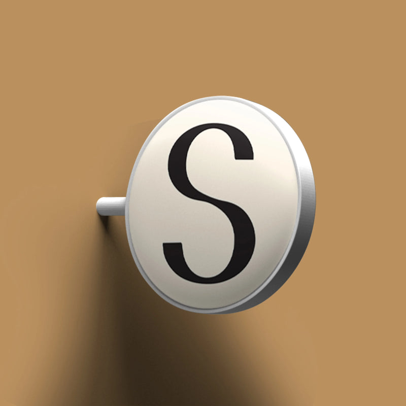 Round metallic object with letter 'S' on a brown background