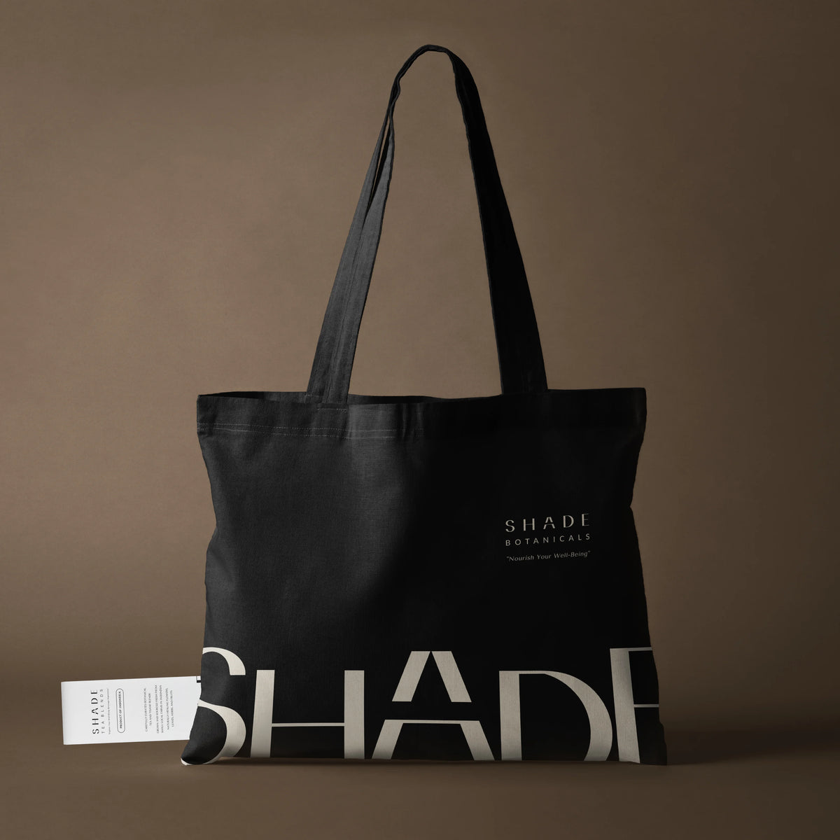 Black tote bag with 'SHADE' branding on a brown background