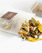 Shade Botanicals Citrus Green loose leaf tea slightly spilled from a small tea pack